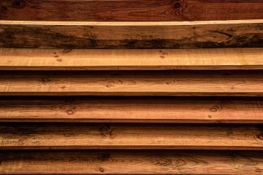 Yatay olarak istiflenmiş koyu renkli ahşap döşemeler kırsal dokulu bir arka plan oluşturuyor..
