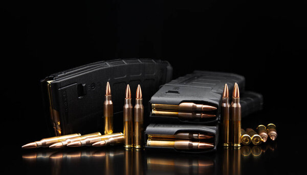 Винтовки и магазин, блестящая латунь на отражающем черном фоне.