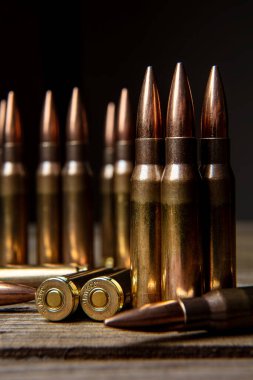Tüfek mühimmatı siyah bir arka plana karşı koyu bir ahşap yüzeyde duruyor ve yatıyor..