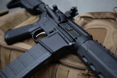 Modern siyah tüfek / şarjörü taktiksel bir sırt çantasında dinleniyor..