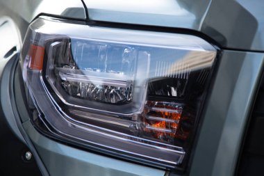 Gri-yeşil bir kamyonetin modern LED far montajının yakın çekimi..