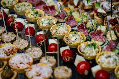 Yemek servisi aperatifleri arasında turtalar, salam kanepeleri ve domatesler de var..