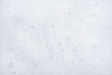 Beyaz sabunlu köpüklü arka planda küçük kabarcıklar var. Üst görünüm.