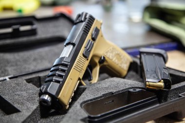 Modern bronz tenli ve siyah yarı otomatik tabancalı koruyucu köpüklü bir çantada..