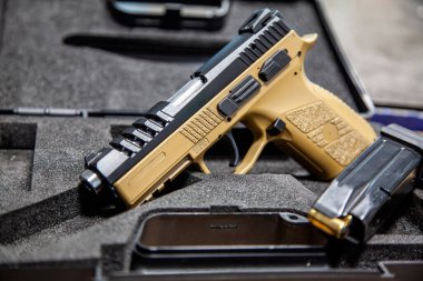 Modern bronz tenli ve siyah yarı otomatik tabancalı koruyucu köpüklü bir çantada..