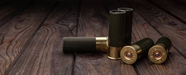 Koyu renk ahşap yüzeyde pirinç bazlı yeşil 12 kalibrelik av tüfeği mermileri..