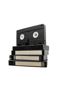 Beyaz arkaplanda boş etiketli eski siyah VHS video kaset yığını.
