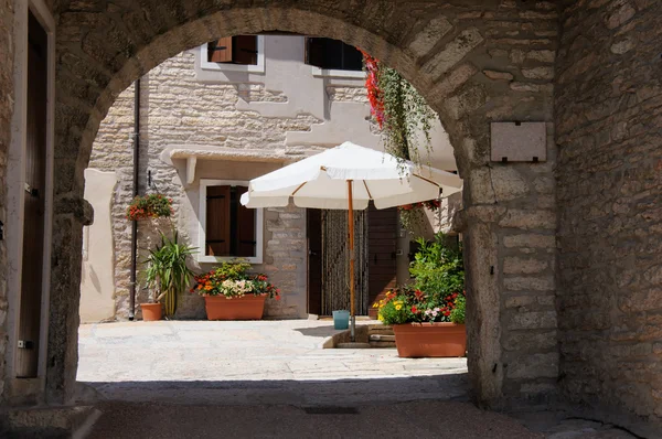 Ein hübscher Innenhof mit Sonnenschirm, bunten Blumen und Holztüren, — Stockfoto