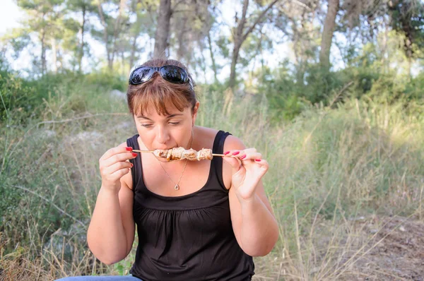 Женщина ест шашлык — стоковое фото