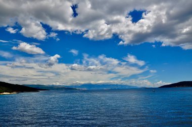 Güzel beyaz bulutlu manzaralı bir gökyüzü. Ada ve anakara arasındaki deniz geçişinin panoramik görüntüsü.