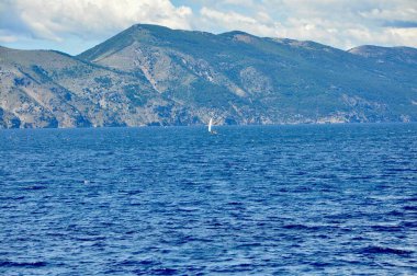 Adriyatik Denizi 'nde, dağın altında yelken açan tekne..
