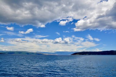 Güzel beyaz bulutlu manzaralı bir gökyüzü. Ada ve anakara arasındaki deniz geçişinin panoramik görüntüsü.