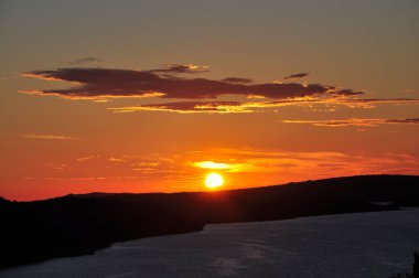 Orange sunset over mountains on a ocean coastline