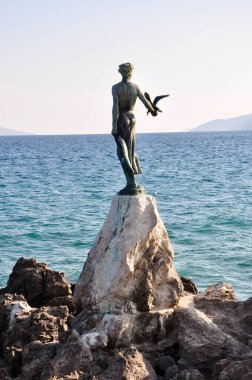 Hırvatistan, Opatija 20 Mart 2021. Hırvatistan 'ın Adriyatik kıyısındaki Opatija sahilinde elinde kuşla duran kızın heykeli. Bölgenin bir simgesi olarak 1956 yılında dikilen ünlü heykel.