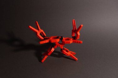 Mandallar, turuncu renkli marangozluk kıskaçları ahşap bir masada yatıyor. Kıskaçtan yapılmış robot şeklinde bir piramit.