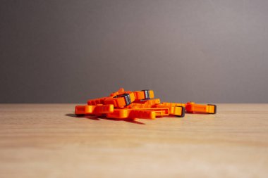 Mandallar, marangozluk kıskaçları, turuncu renkli tahta bir masanın üzerinde yatıyor..