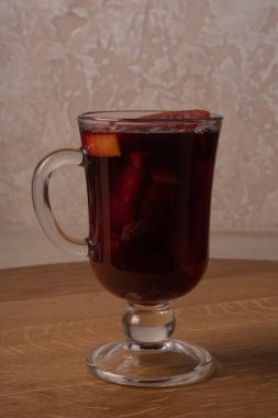 Elma ve portakallı bir kadeh kırmızı şarap ahşap bir masada..