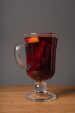 Elma ve portakallı bir kadeh kırmızı şarap ahşap bir masada..