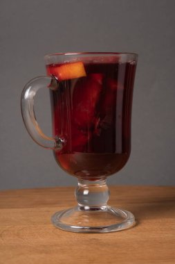 Elma ve portakallı bir kadeh kırmızı şarap ahşap bir masada.