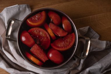 Kırmızı şarap, elmalı ve portakallı şarabı paslanmaz çelikten bir tencereyle evde hazırlarken...