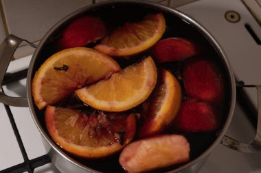 Kırmızı şarap, elmalı ve portakallı şarabı paslanmaz çelikten bir tencereyle evde hazırlarken....