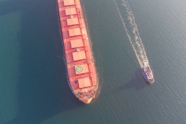 Kuru kargo gemisi römorkörlerin yardımıyla limana giriyor. Bir helikopterden fotoğraf. Kuş bakışı görünüm