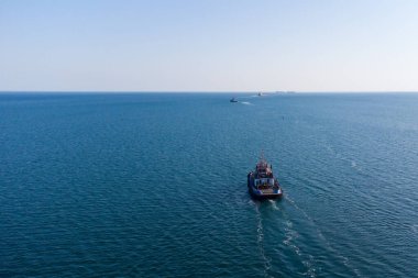 Deniz römorkörü liman su alanından açık denize doğru hareket ediyor. Helikopterden bir fotoğraf. Yukarıdan görüntüle