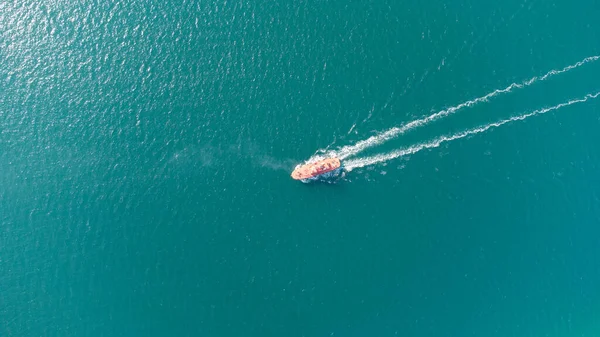 The pilot boat orange goes to meet the vessel on the outer roads. Helicopter view. Top view of the sea