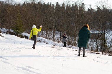 Genç insanlar ve çocuklar kışın dağlık arazide karda dışarıda oynarlar.