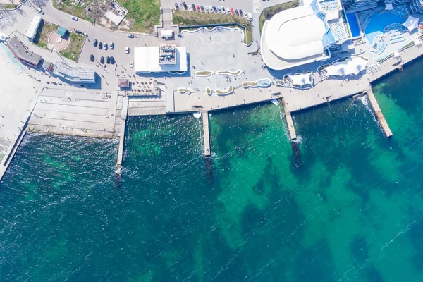 Sandy beach, concrete pier, clear sea water. Helicopter view