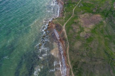Dik deniz kıyısı ve sörf. Deniz suyu, kum üstüne fırtına ve yosun ile çamurlu. Hava görünümü