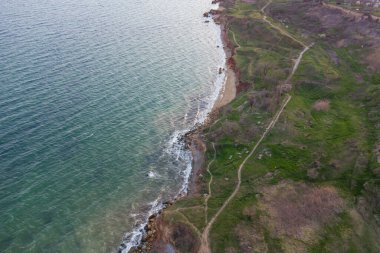 Dik deniz kıyısı ve sörf. Deniz suyu, kum üstüne fırtına ve yosun ile çamurlu. Hava görünümü