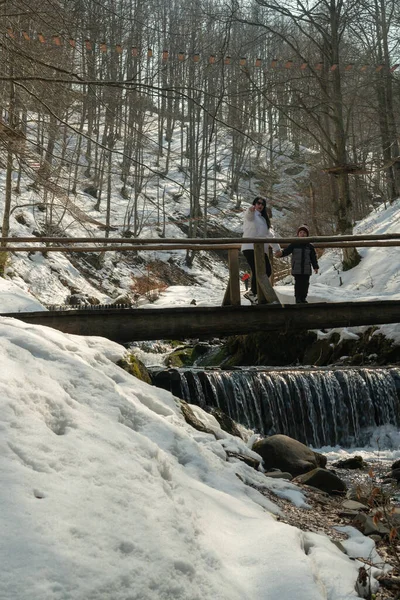 Une femme avec un enfant sur un pont en bois au-dessus d'une rivière de montagne. Carpates. Ukraine. — Photo