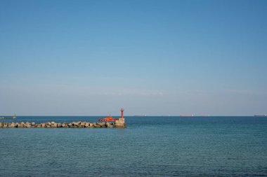 Turuncu bir pilot botu, geminin limana kadar eşlik etmesi için dış yola çıkıyor.