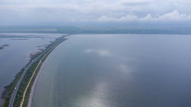 Deniz ve haliçler arasında dar bir tükürük boyunca uzanan bir otoyol. Arabalar yolda. Hava görünümü