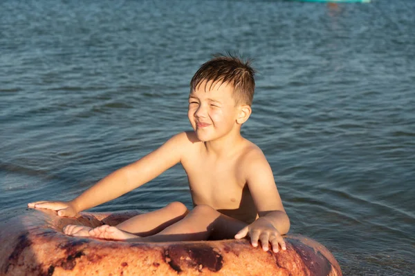 Chłopiec w wieku 6 lat pływa na nadmuchiwanym pierścieniu w morzu niedaleko brzegu. — Zdjęcie stockowe