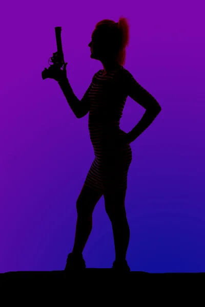 Siluet seorang wanita dalam tumit dan gaun dengan pistol berdiri di samping — Stok Foto
