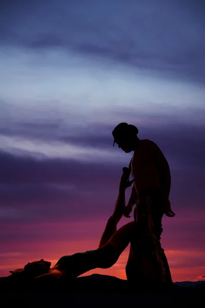 Silhouette of a woman laying on back leg up on cowboy — Stock Photo, Image