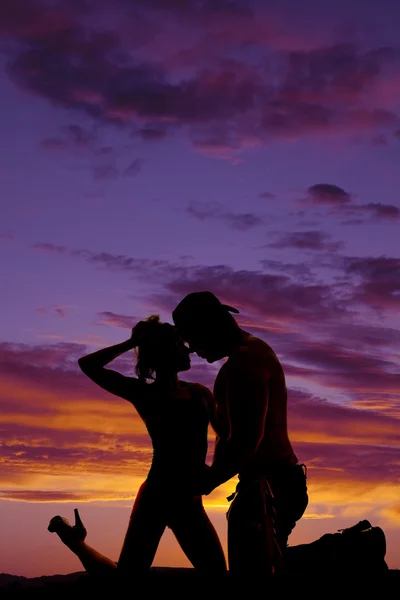 Silhouette einer Frau in einem lila Sonnenuntergang auf Knien von Cowboy — Stockfoto