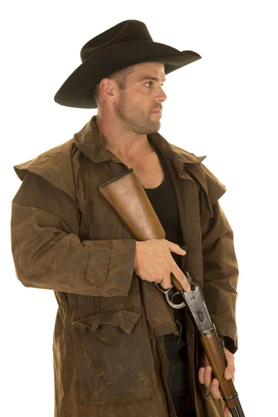 Cowboy in black hat and duster holding rifle look to side — Stock Photo, Image