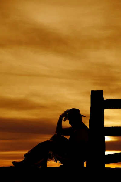 Silhouette de cow-boy assis par la poste regarder vers le bas — Photo