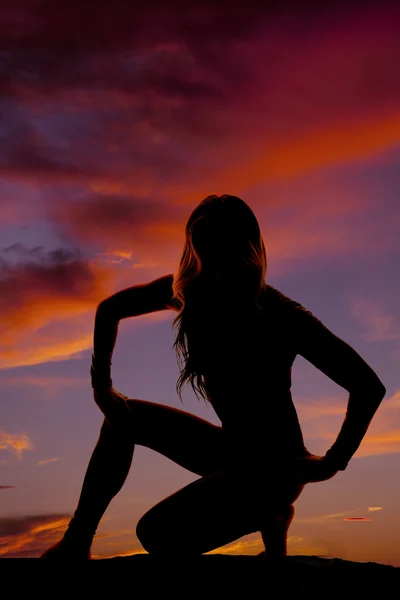 Silueta de una mujer abajo con la mano sobre una rodilla al atardecer — Foto de Stock