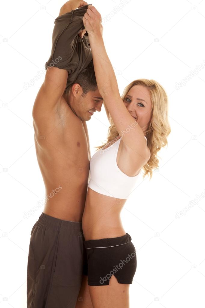 woman lifting mans shirt over his head