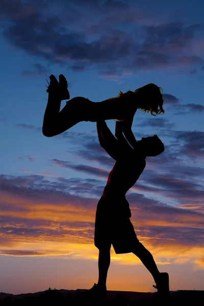 Silhouettes of man throw woman up — Stock Photo, Image