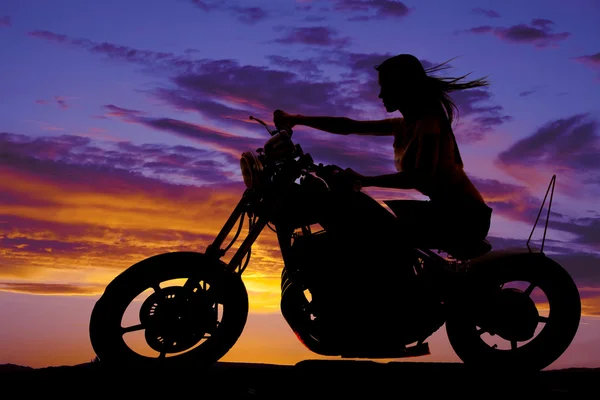 Silhuetten av en kvinna på en motorcykel vinden blåser — Stockfoto