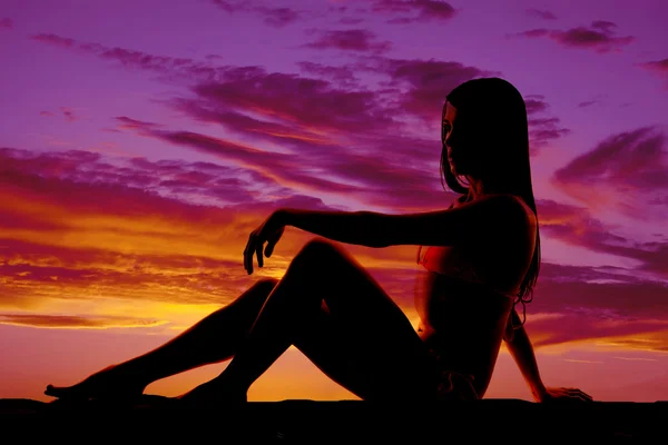 Silhouette of woman in bikini sitting on hand back one on knee — Stock Photo, Image