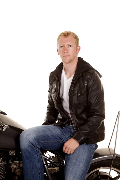 Man in zwarte jas motorfiets zitten zijwaarts — Stockfoto