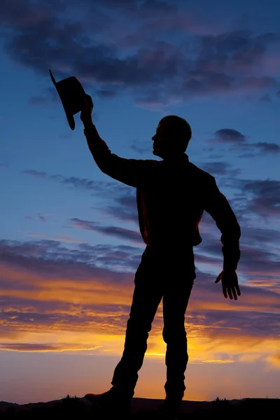 Silhouette Cowboy hält Hut mit Hand hoch — Stockfoto