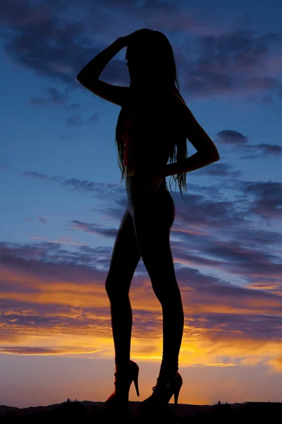 Жінка силует стоїть на високих підборах руки на голову і стегно — стокове фото