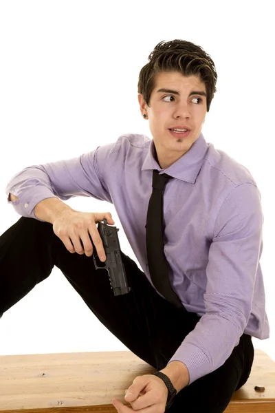 Man in purple dress shirt and gun sit look back Stock Picture